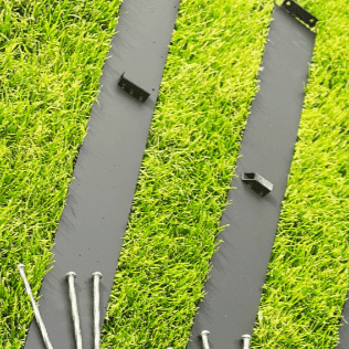 Metal Edging Laying on Grass with stakes on top of edging