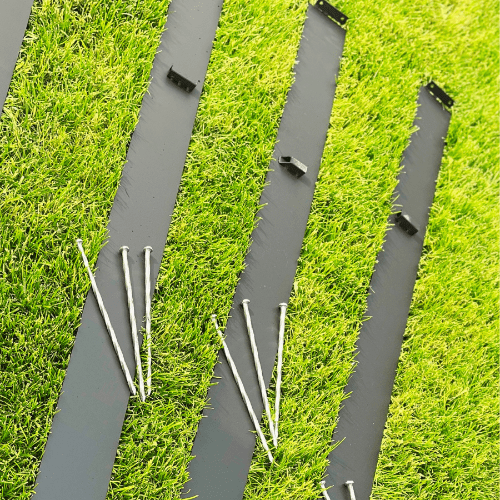 Metal Edging Laying on Grass with stakes on top of edging