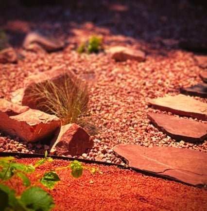 4 inch tall Metal Edging shown in between two types of red rocks in a desert landscape designed by professional landscapers